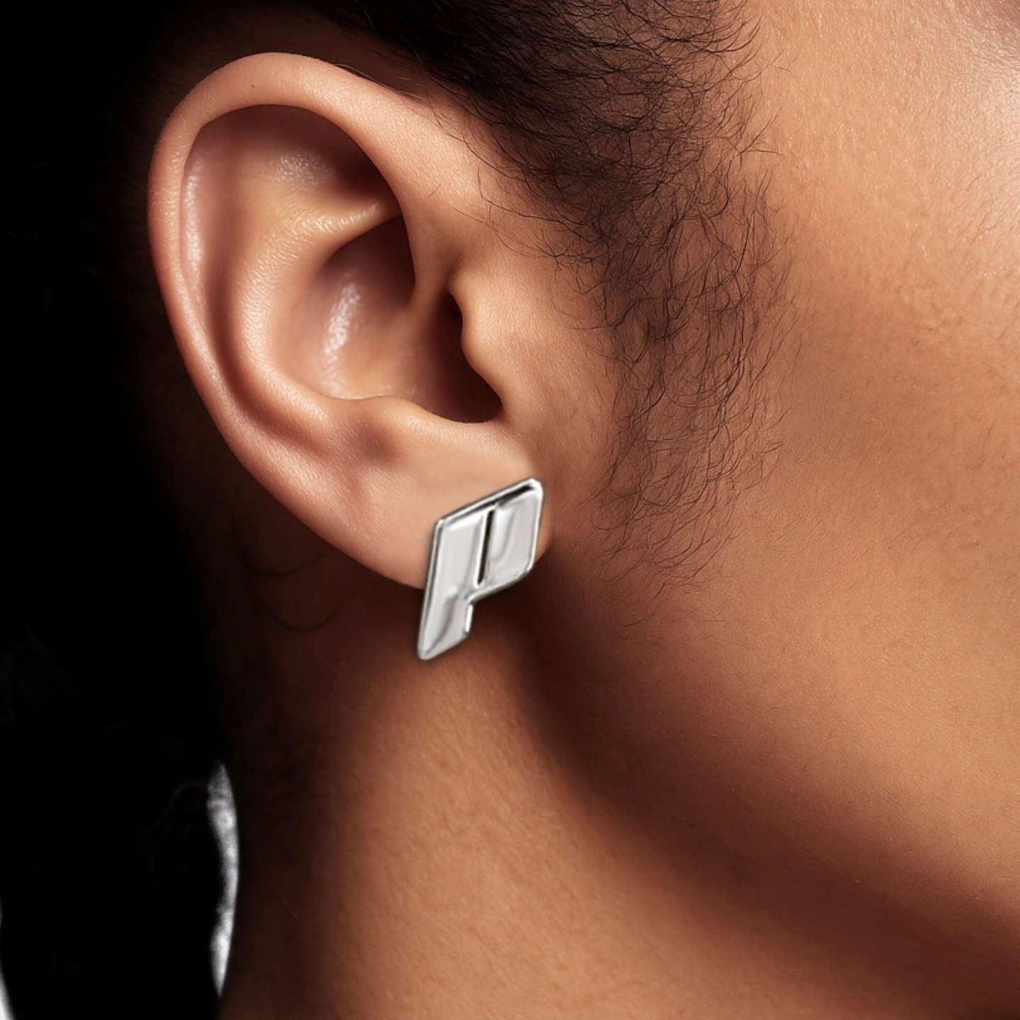 A close up view of the Play Monogram Large Stud Earring in Sterling Silver worn by model